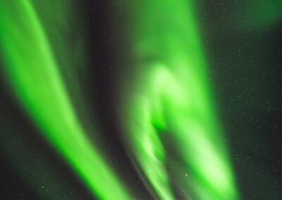 Vibrant green aurora borealis lights up a starry night sky.